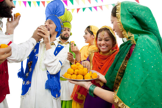 Sikh people eating laddoos 