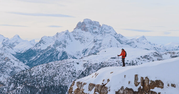 Ski mountaineer standing on a snowy cliff in the Dolomites with majestic alpine peaks in the background, capturing winter adventure, solitude and breathtaking mountain scenery.