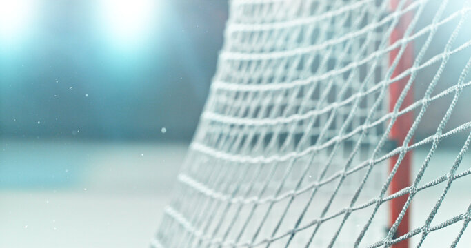 Close-up detail of an ice hockey goal net inside an indoor rink, with shallow depth of field and blurred background, capturing sports atmosphere and texture of the net mesh.