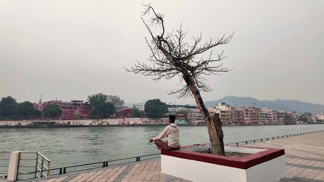 Man meditating by river near Ganga ghat in rishikesh Uttarakhand for spiritual peace
