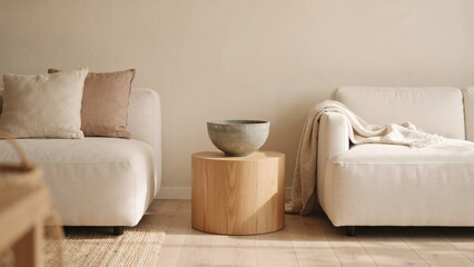 Minimalist living room interior showing two cream sofas beside a round wooden side table with separated cylindrical wooden displays serene living © Sanoor