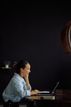 Happy Korean businesswoman using laptop while working in office