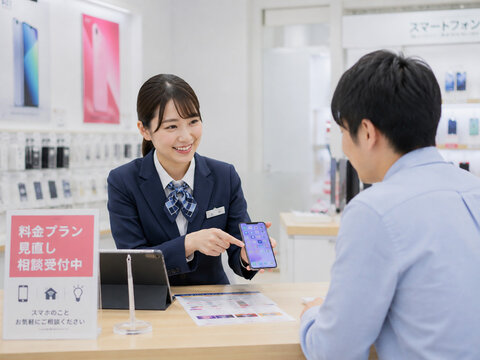スタッフが顧客にスマートフォンや料金プランを説明・提案している場面