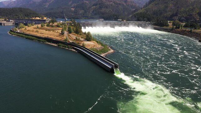 4K aerial drone footage of Bonneville Dam in Columbia River Gorge, Oregon, USA, releasing powerful water through spillways between Oregon & Washington, showcasing hydroelectric power, renewable energy