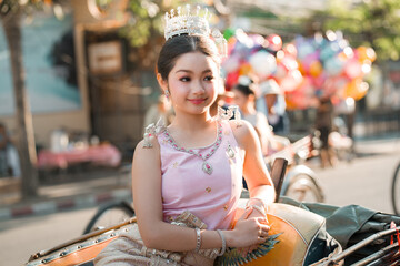 Young Girl Wearing Crowning Tiara and Elegant Dress Sitting on Motorcycle at Festival © phaitoon