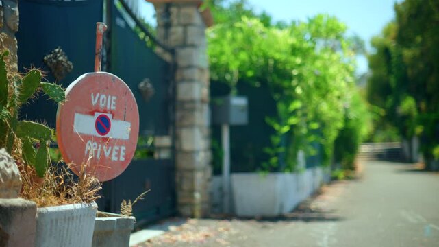 Private road sign Voie Privee on an old round plaque, indicating restricted access and privacy at a gate entrance