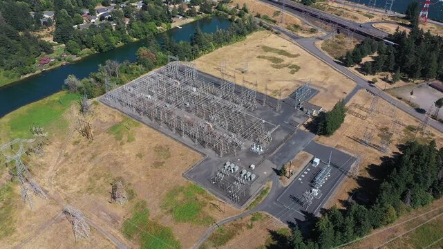 4K aerial drone footage of electrical substation near Bonneville Dam, Washington, USA, showing transformers, power lines and transmission infrastructure surrounded by Columbia Gorge landscape