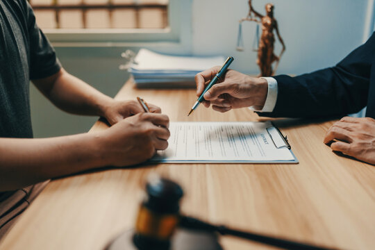 Client and lawyer reviewing important legal documents, finalizing an agreement in an office setting with justice scales