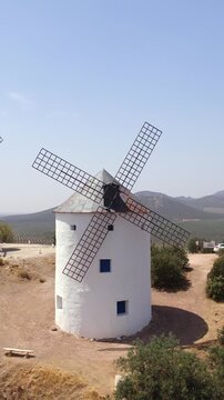 White windmills perched on a hill in PuertoLapice, Castilla La Mancha, Spain, framing a clear blue sky on a sunny summer day
