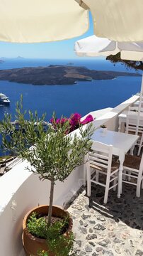 Santorini island, Greece. Traditional greek cafe on the terrace with sea view. Blue sea and the blue sky at sunny day. Travel and summer vacation concept. Vertical video
