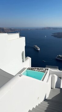 White architecture in Santorini island, Greece. Luxury swimming pool with blue water. Blue sea and the blue sky at sunny day. Travel and summer vacation concept. Vertical video
