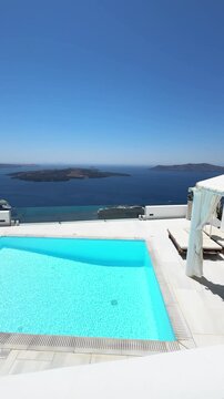 White architecture in Santorini island, Greece. Luxury swimming pool with blue water. Blue sea and the blue sky at sunny day. Travel and summer vacation concept. Vertical video
