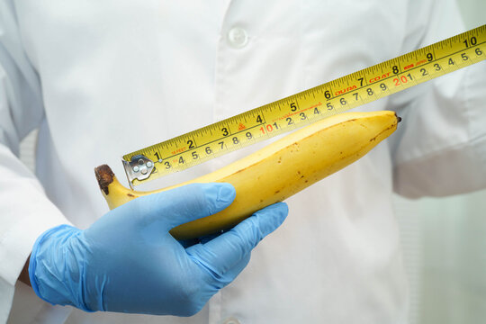 Male doctor stands holding a banana, penis health.