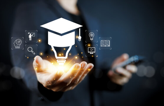 Business man holding glowing graduation cap lightbulb icon. Concept of online education, e-learning, skill development, and digital knowledge innovation for career success and future growth.