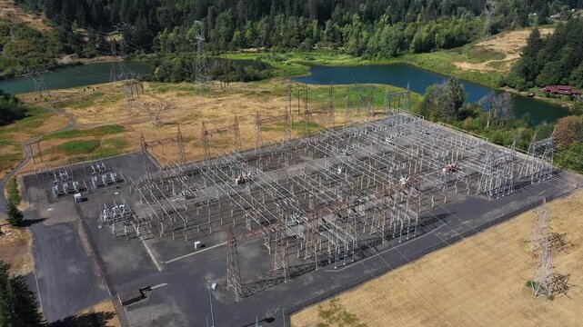 4K aerial drone footage of electrical substation near Bonneville Dam, Washington, USA, showing transformers, power lines and transmission infrastructure surrounded by Columbia Gorge landscape