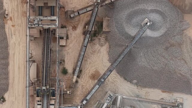 An aerial view reveals a large industrial quarry, with conveyor belts efficiently moving raw aggregate materials across the extensive processing plant.
