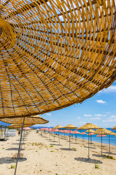 Sunny beach near cunda island on the aegean coast in turkey with straw umbrellas and turquoise sea. Travel, relaxation and summer vacation concept. 