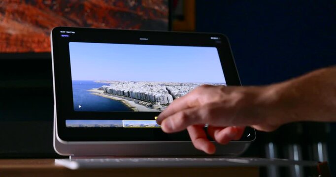 Hand touching tablet screen to edit video timeline on Final Cut Pro in home studio. Close-up
