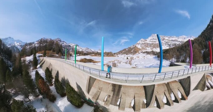 Aerial view of concrete Orden Dam with decorative colorful pillars surrounded by snow in Maloja Pass, Switzerland