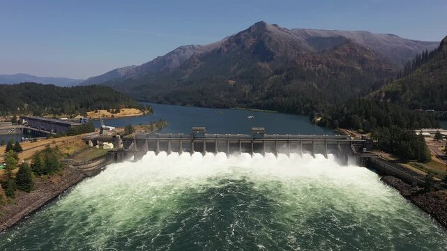 4K aerial drone footage of Bonneville Dam in Columbia River Gorge, Oregon, USA, releasing powerful water through spillways between Oregon & Washington, showcasing hydroelectric power, renewable energy