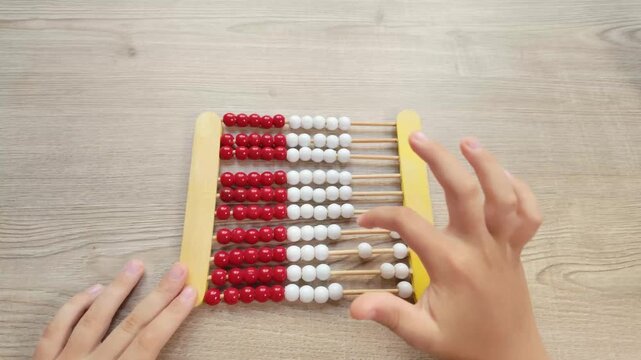 Child Hands Counting on a Wooden Abacus at Table