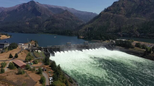 4K aerial drone footage of Bonneville Dam in Columbia River Gorge, Oregon, USA, releasing powerful water through spillways between Oregon & Washington, showcasing hydroelectric power, renewable energy