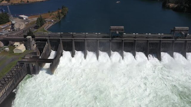 4K aerial drone footage of Bonneville Dam in Columbia River Gorge, Oregon, USA, releasing powerful water through spillways between Oregon & Washington, showcasing hydroelectric power, renewable energy