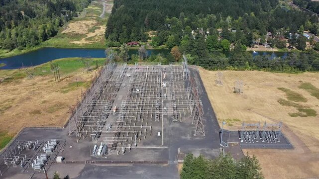 4K aerial drone footage of electrical substation near Bonneville Dam, Washington, USA, showing transformers, power lines and transmission infrastructure surrounded by Columbia Gorge landscape
