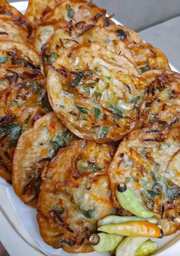 Freshly cooked Indonesian fried vegetable fritters served with fresh chili peppers on a plate