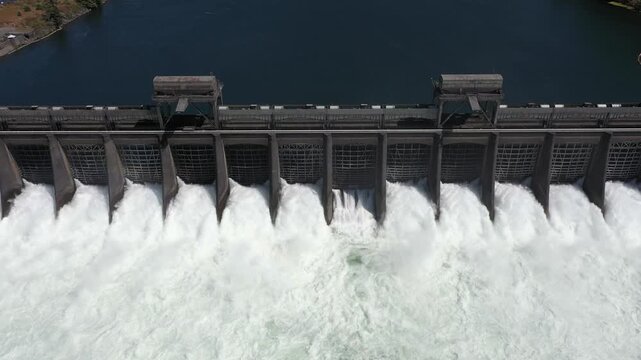 4K aerial drone footage of Bonneville Dam in Columbia River Gorge, Oregon, USA, releasing powerful water through spillways between Oregon & Washington, showcasing hydroelectric power, renewable energy