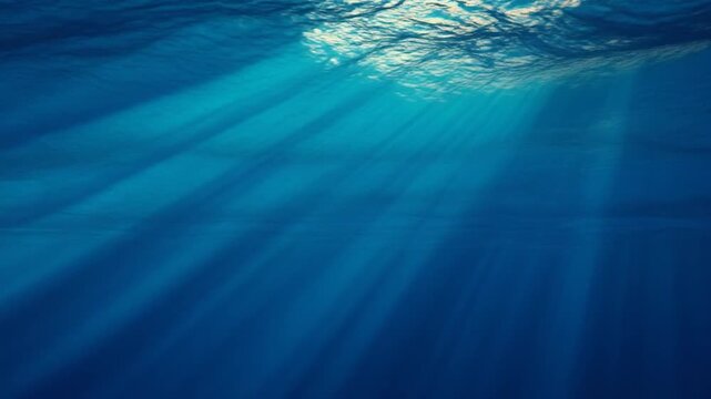 Sunlight beams through ocean surface water in deep blue sea during daytime