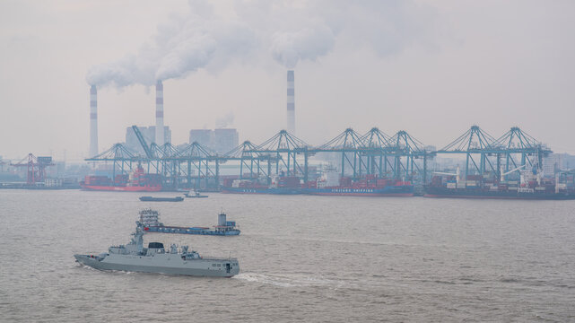 Port of Shanghai scenic view with Chinese military vessel sailing in the port and container cranes in Shanghai China