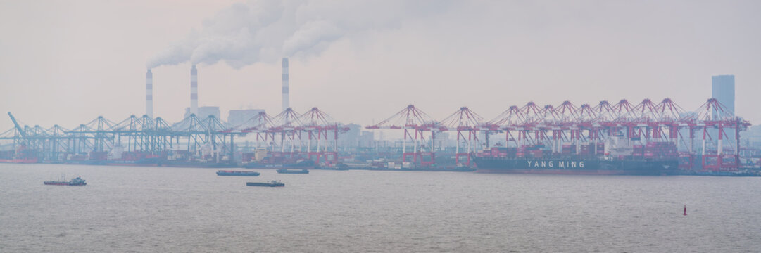 Port of Shanghai panoramic view with container vessel in the port and container cranes and smog in Shanghai China
