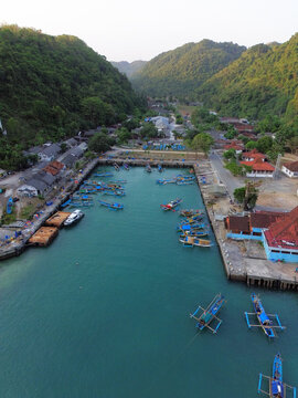 Aerial Drone View of Traditional Fishing Boats Moored at Sadeng Fishing Port During Sunset, Yogyakarta, Indonesia