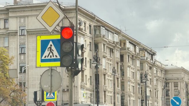 A red traffic light and road signs pass by a car window against a historic building in Saint Petersburg. This fleeting urban view inspires calm patience and quiet safety.