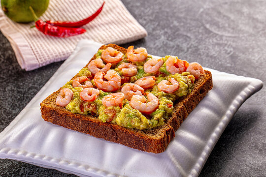 Shrimp avocado toast on dark bread with chili and lime