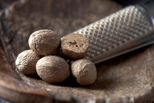 A brass trowel holds nutmeg and a grater indoors