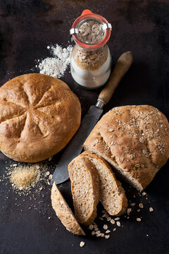 Two spelt breads and glass bottle of ingredients for preparing spelt bread