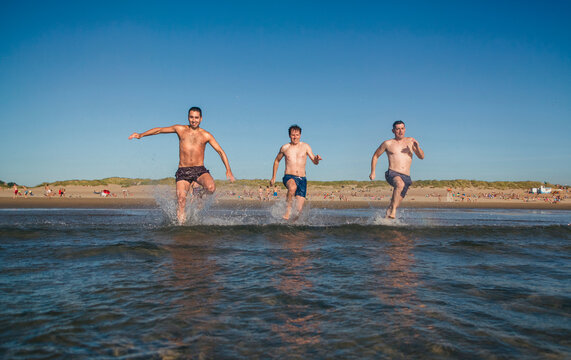Friends running and jumping into the sea