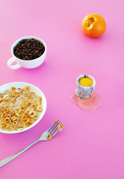 Surreal messy breakfast flat lay with cereal coffee and egg on pink