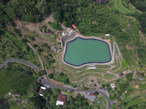 Aerial drone footage of Embung Nglanggeran, a scenic artificial reservoir located in the Ancient Nglanggeran Volcano area, Yogyakarta, Indonesia.
