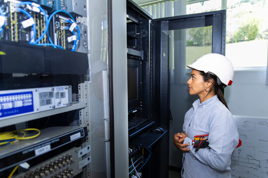 Female technician checking wire in an indoor electrical control box