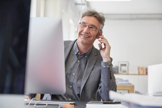 Mature businessman working in office, talking on the phone 