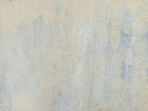 A close-up view of a raw concrete wall showing fine cracks, brush strokes, and uneven textures.