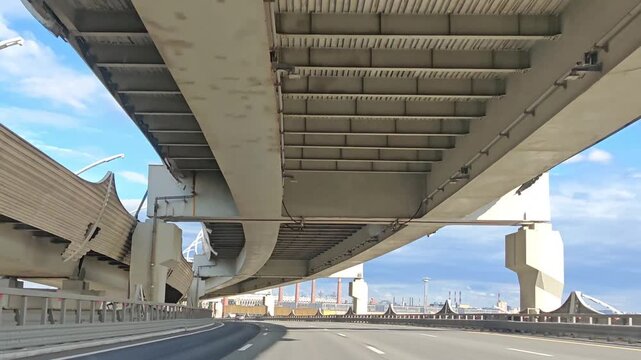 View from below of concrete highway overpass with steel beams against cloudy sky, urban bridge infrastructure, transport construction, engineering structure, road viaduct