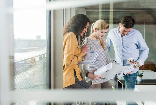 Three colleagues looking at plan in office 