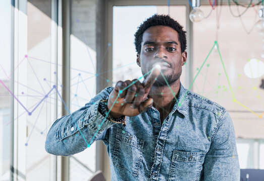 Casual businessman touching glass pane with diagram in office