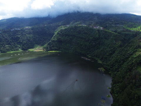 Aerial drone footage of Telaga Menjer, a beautiful volcanic lake located near the Dieng Plateau in Wonosobo, Central Java, Indonesia. Surrounded by lush green hills and spectacular mountain scenery