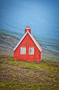 Iceland, Europe: a small, iconic, isolated wooden cottage on the road along the East Fjords landscape, shrouded in fog
