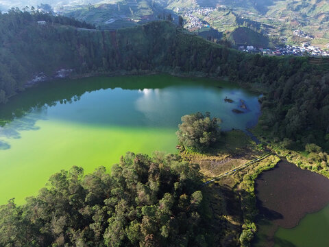 Aerial drone footage of Telaga Warna (Color Lake) on the Dieng Plateau, Central Java, Indonesia, captured during the late afternoon golden hour